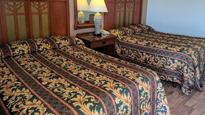 Una habitación de hotel con dos camas, una mesita de noche, una lámpara y un espejo.