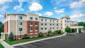 A multi-story hotel with a central entrance and a parking lot. - SpringHill Suites by Marriott Long Island Brookhaven (Yaphank)