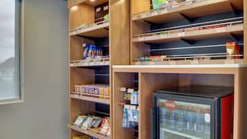 A vending machine stocked with beverages and a refrigerator.