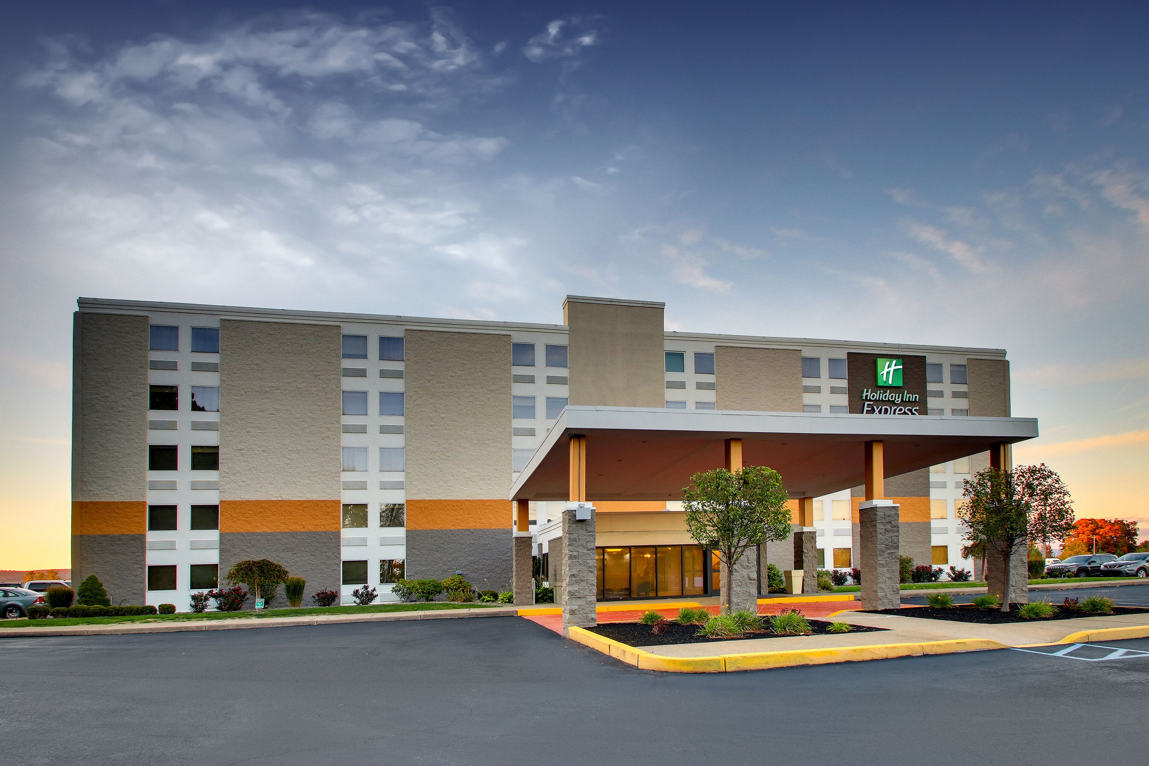 A Holiday Inn Express building with a covered entrance, multiple windows, and a parking lot.
