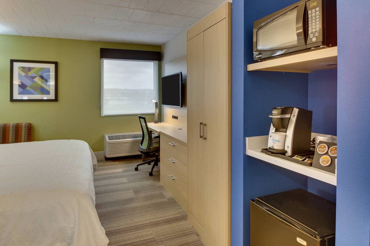 Une chambre d’hôtel équipée d’un lit, d’un bureau, d’un ordinateur, de la climatisation, d’une machine à café et d’un four à micro-ondes.