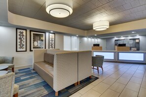Un hall de hotel con mostrador de recepción, zona de estar con separadores estampados y obras de arte enmarcadas en las paredes.