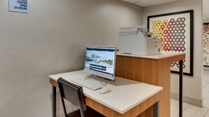 Ein Businesscenter mit Computer, Stuhl und Schild, das einen 24-Stunden-Betrieb anzeigt.