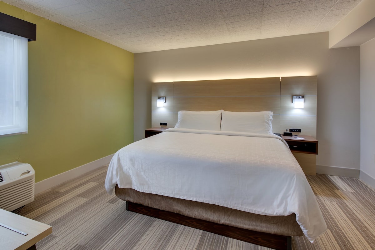 Une chambre d’hôtel moderne avec un grand lit, des tables de chevet et un luminaire fixé au mur.