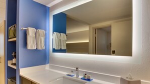 Ein modernes Badezimmer mit einem weißen Waschbecken, blauen Wänden und einem großen Spiegel.