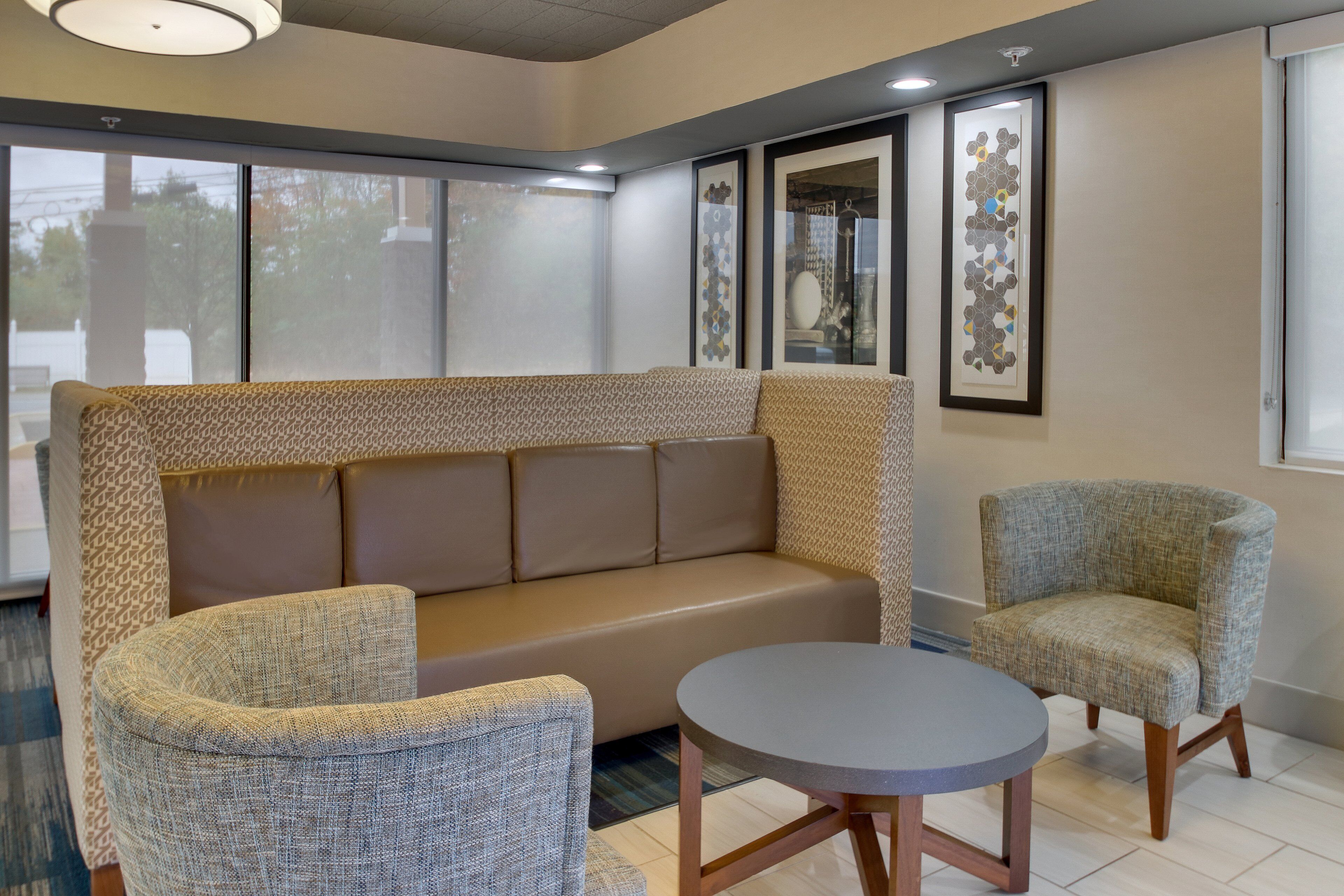A modern lounge area with a sofa, two armchairs, and a small round table.