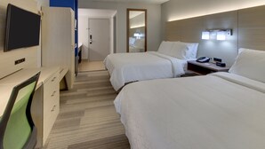 Ein Hotelzimmer mit zwei Betten, einem Schreibtisch mit Stuhl, einem Fernseher und einem Spiegel.