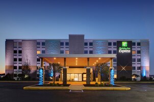 Un hotel Holiday Inn Express con fachada moderna, amplias ventanas y una entrada bien iluminada.