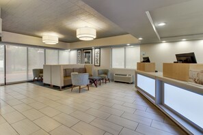 A modern hotel lobby with a reception desk, seating area, and large windows. - Holiday Inn Express Pittston - Scranton Airport by IHG (Pittston)