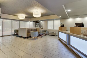 Un moderno vestíbulo de hotel con un mostrador de recepción, zona de estar y grandes ventanales.