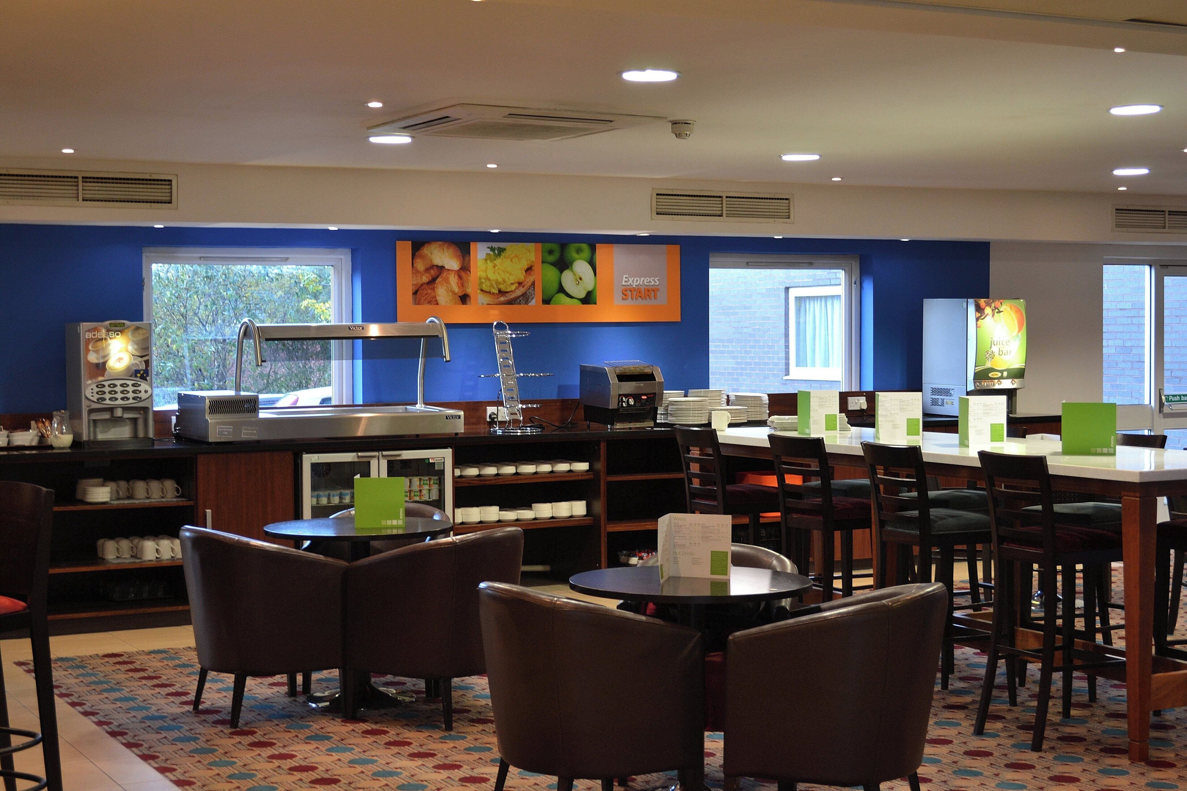 A restaurant with a coffee machine, seating area, and a menu board.