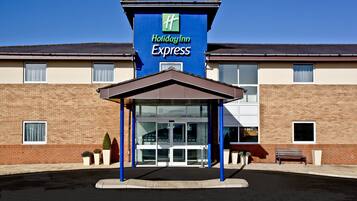 A Holiday Inn Express building with a clear entrance, a covered waiting area, and a brick facade.