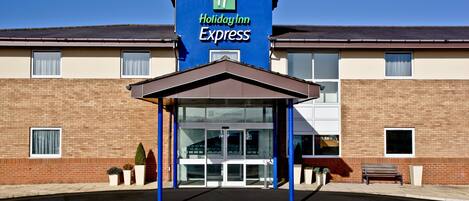 A Holiday Inn Express building with a clear entrance, a covered waiting area, and a brick facade.