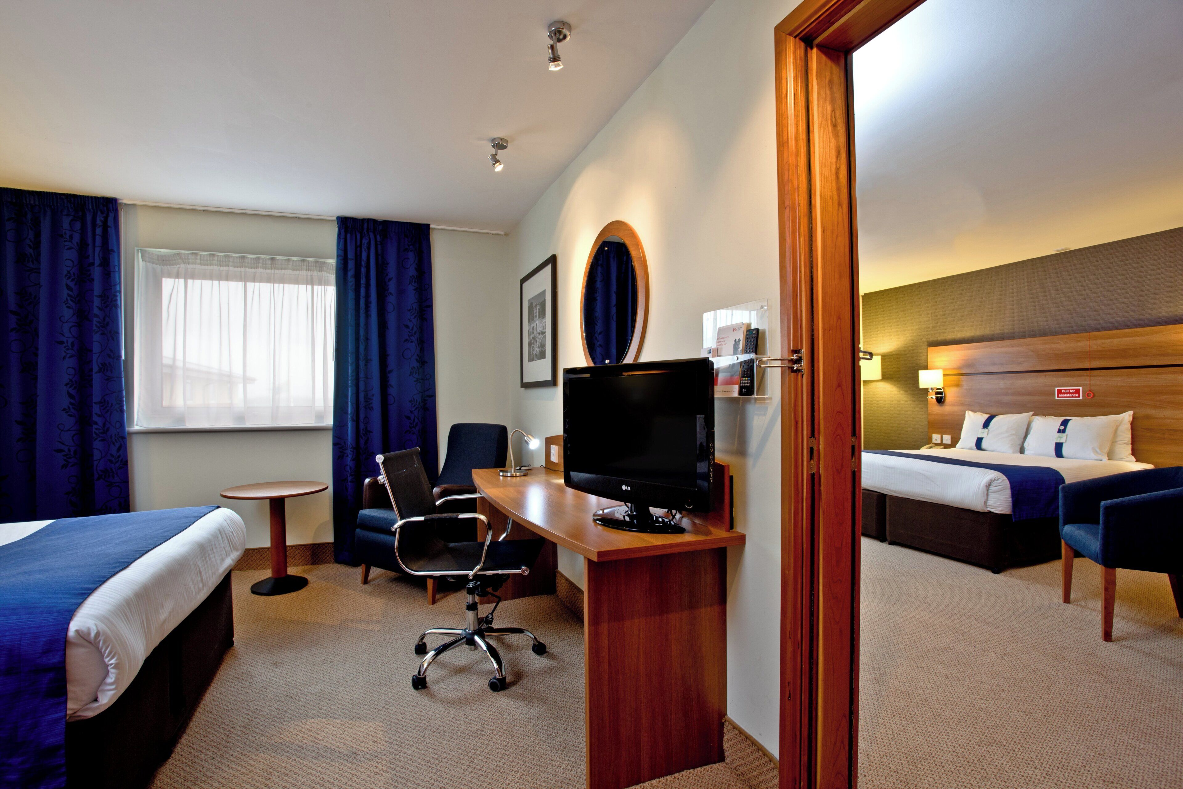 Une chambre d’hôtel équipée d’un lit, d’un bureau, d’une chaise, d’une télévision et d’une petite table.