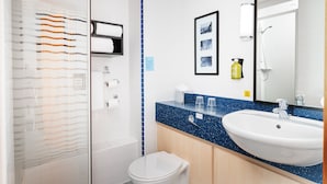 A modern bathroom with a white toilet, a shower with a glass door, a sink with a blue speckled countertop, and a large mirror.