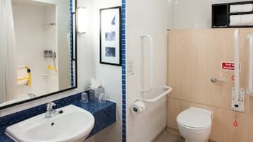 A bathroom with a sink, mirror, toilet, and handrails.
