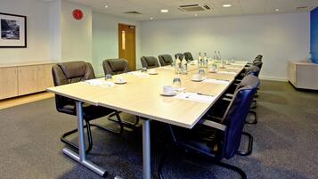 A conference room with a long table, chairs, and various items like water bottles and papers.