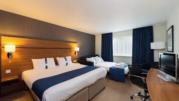 A hotel room with two beds, a desk, a chair, a television, and a window with curtains.