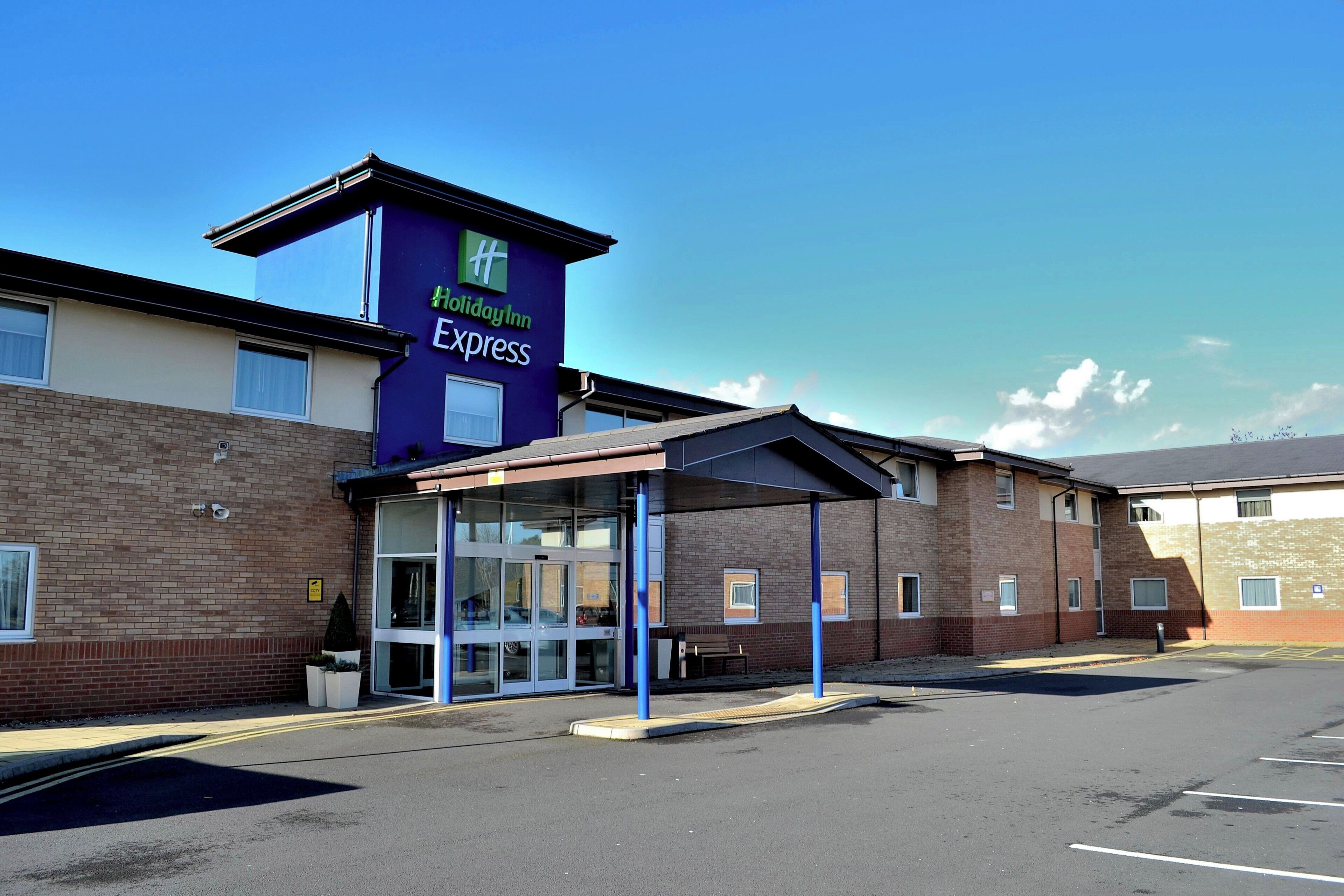 Edificio de Holiday Inn Express con entrada cubierta y estacionamiento.