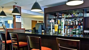 A bar area with multiple stools, a bar counter, and a variety of bottles and glasses. - Holiday Inn Express Shrewsbury by IHG (Shrewsbury)