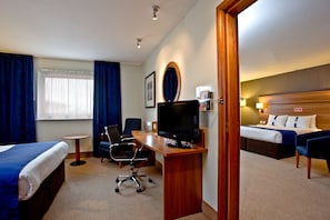 Une chambre d’hôtel avec un lit, un bureau, une chaise, une télévision et une petite table.