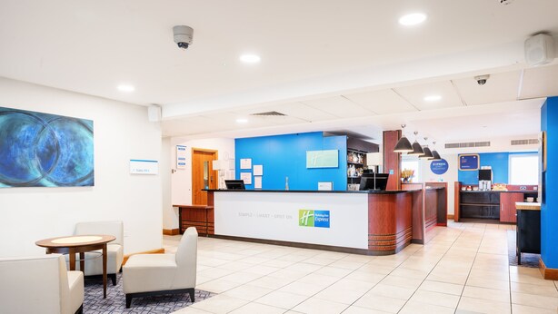 A hotel reception area with a blue wall, a reception desk, and seating arrangements.