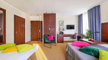 Habitación de hotel con dos camas, un escritorio, una silla, un televisor y una ventana con cortinas.