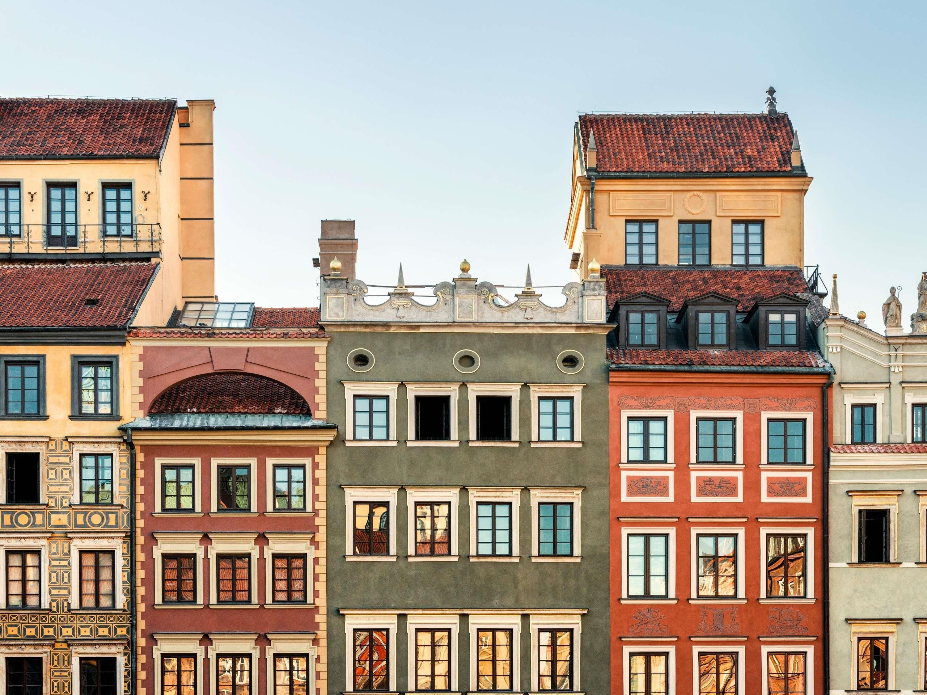 Eine Reihe bunter Gebäude mit unterschiedlichen Architekturstilen, darunter aufwendige Fassaden und verschiedene Fenstergestaltungen.