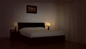 Habitación de hotel con cama, dos lámparas de noche, un cuadro en la pared y una cortina en la ventana.