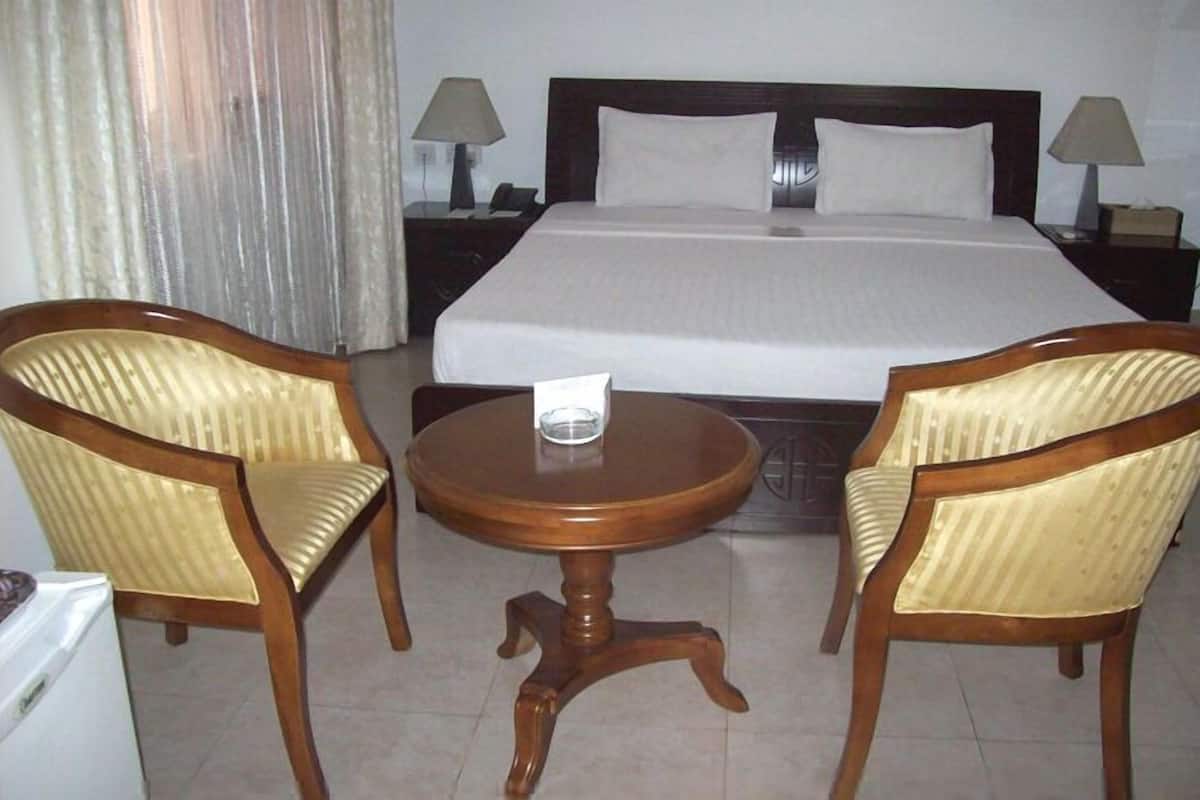 A hotel room with a bed, two armchairs, a small round table, and two bedside lamps.