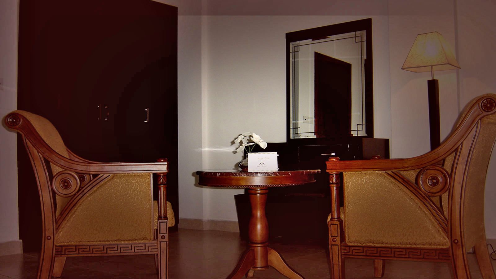 Una habitación con una mesa de madera, dos sillas, un espejo y una lámpara.