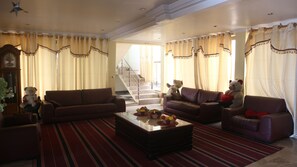 A spacious living room with two sofas, a coffee table, and decorative teddy bears. A staircase is visible in the background leading to another level. - Crown Liberty Hotel (Accra)