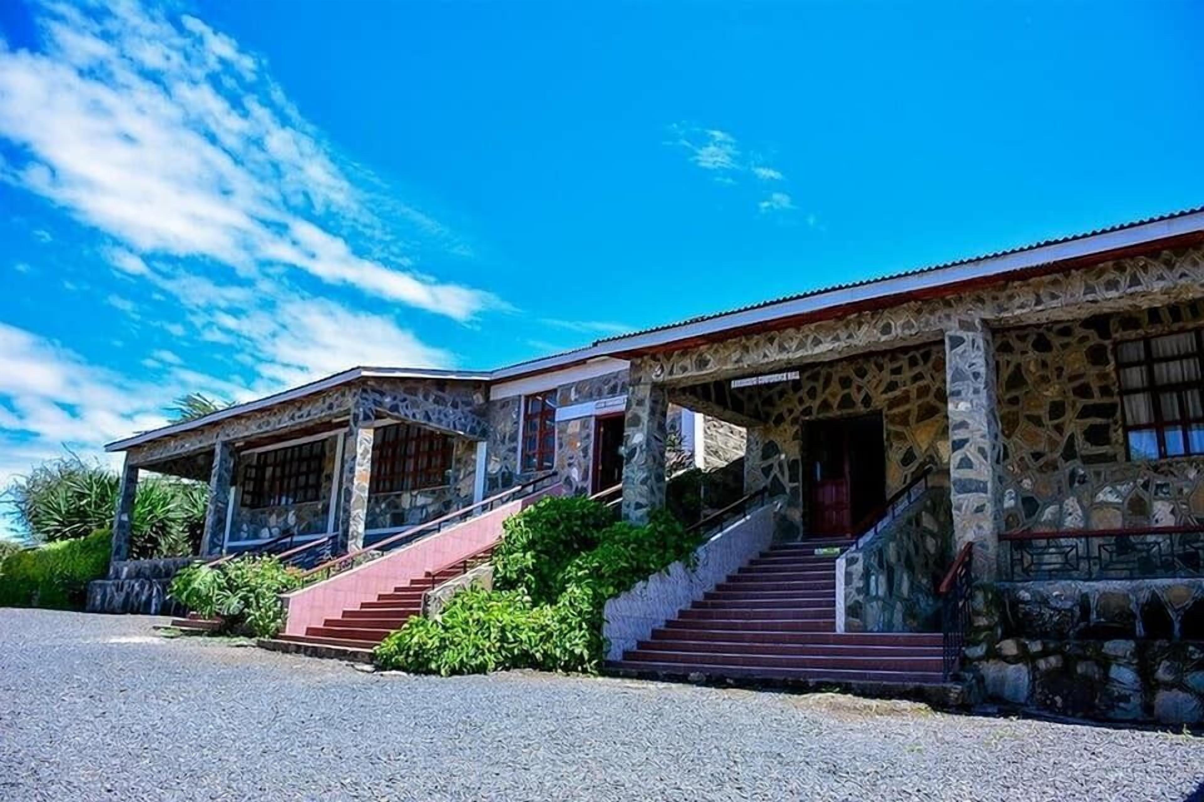 A stone building with a covered porch and a staircase leading to the entrance.