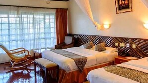 A hotel room with a geometric ceiling design, a bed with patterned pillows, a desk with a chair, and a large window with curtains. - Elementaita Country Lodge (Nakuru)