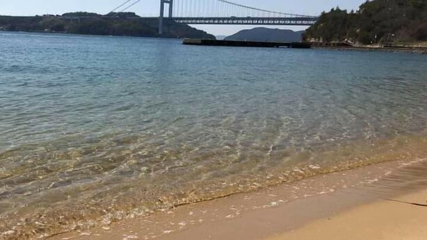 A beach with clear water and a bridge in the background. - Washuzan Shimoden Hotel (Kurashiki)