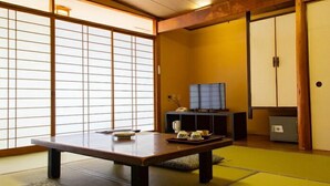 A traditional Japanese room with tatami flooring, a low table with tea set, a television on a stand, and sliding doors. - Washuzan Shimoden Hotel (Kurashiki)