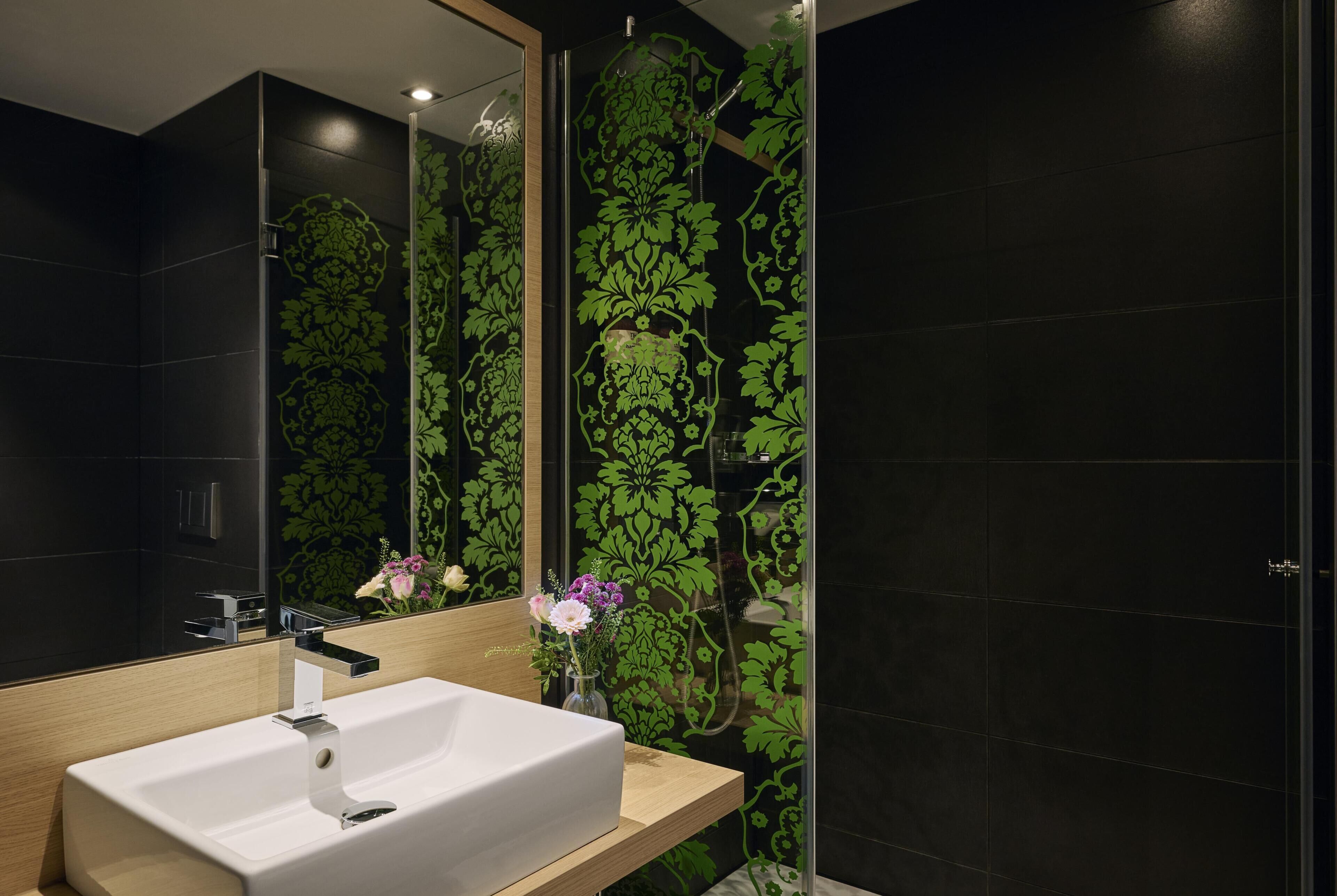 A modern bathroom with a large mirror, a white sink, and a shower.