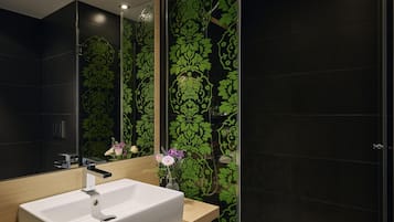 A modern bathroom with a large mirror, a white sink, and a shower.