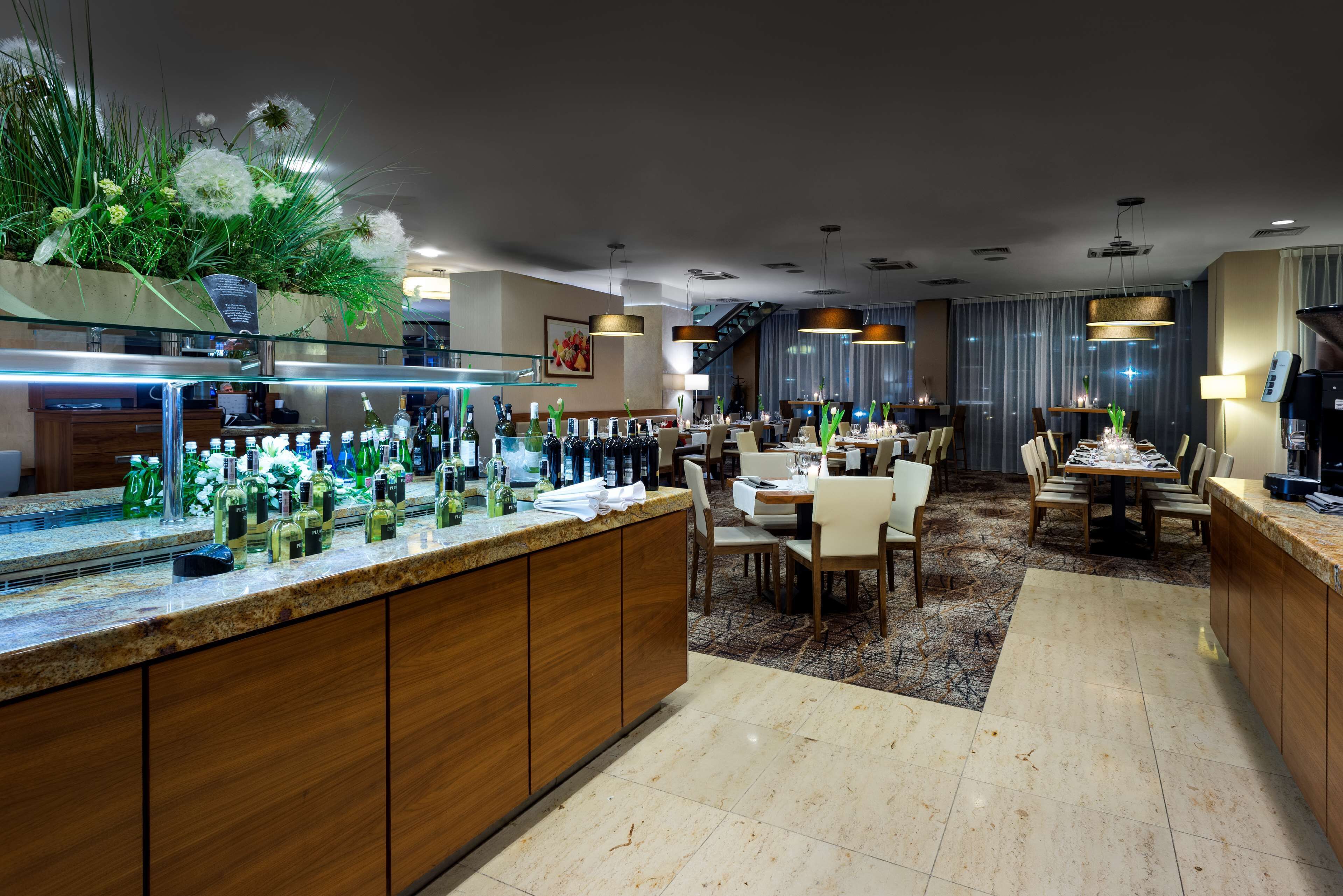 Eine moderne Hotelhalle mit Barbereich, Essbereich und einer Treppe zu einer oberen Ebene.