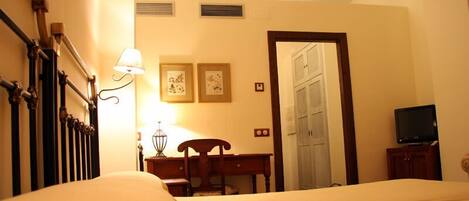 Una habitación de hotel con cama, escritorio, silla, televisor y puerta.