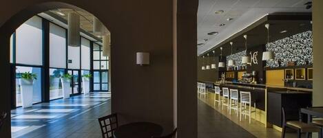 Un interior moderno con comedor, bar y un amplio arco de entrada a un espacio luminoso.