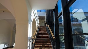 A staircase with wooden steps and black railings leading to a balcony with large windows. - Hospedium Hotel Cortijo Santa Cruz (Villanueva de la Serena)