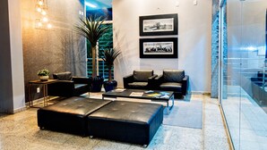A modern lobby with leather seating, a coffee table, and framed pictures on the wall. - Premium Executive Hotel (Itabira)