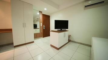 Una habitación con televisión sobre un mueble, un armario y una puerta que da a otra estancia.