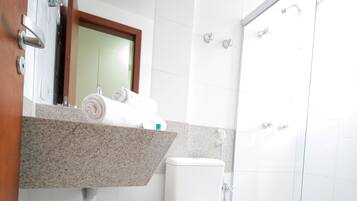 A modern bathroom with a toilet, a shower enclosure, and a vanity with a mirror.