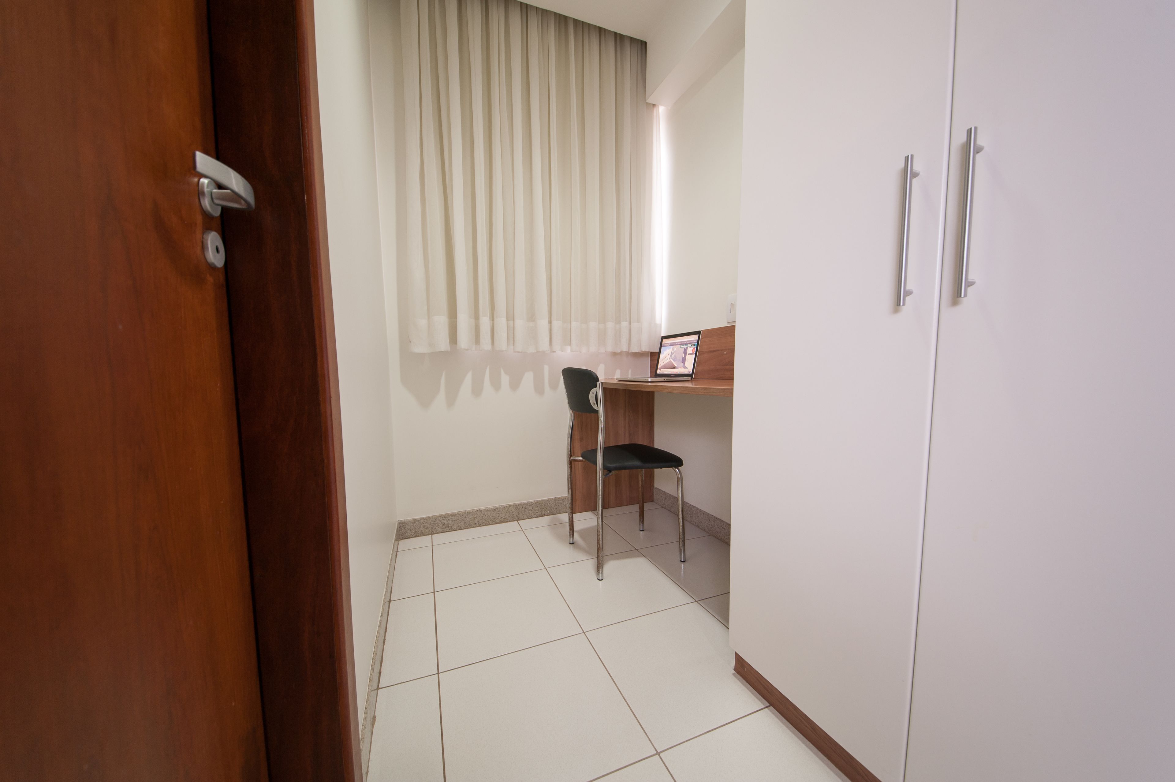 Una habitación con puerta de madera, una silla, un escritorio y un armario.
