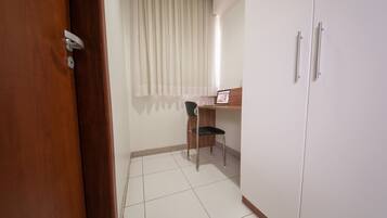 Una habitación con puerta de madera, una silla, un escritorio y un armario.