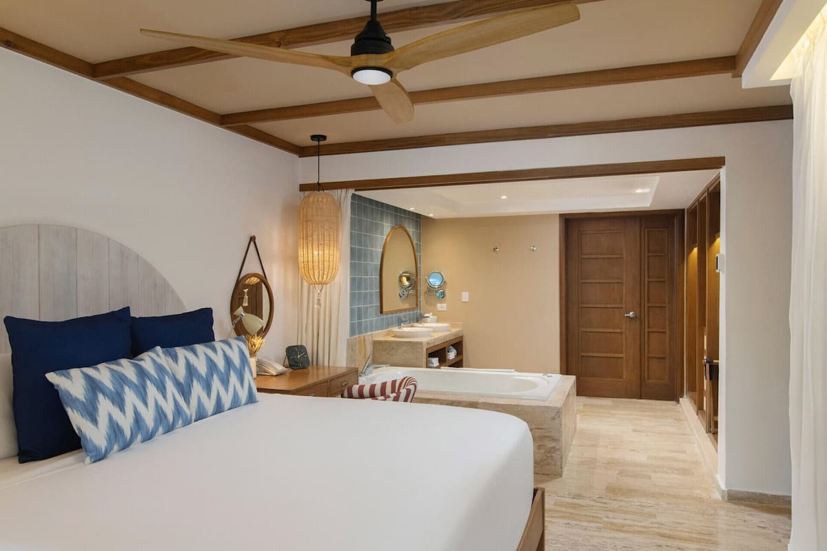 Un dormitorio con cama, mesita de noche, lámpara y un espejo grande.
