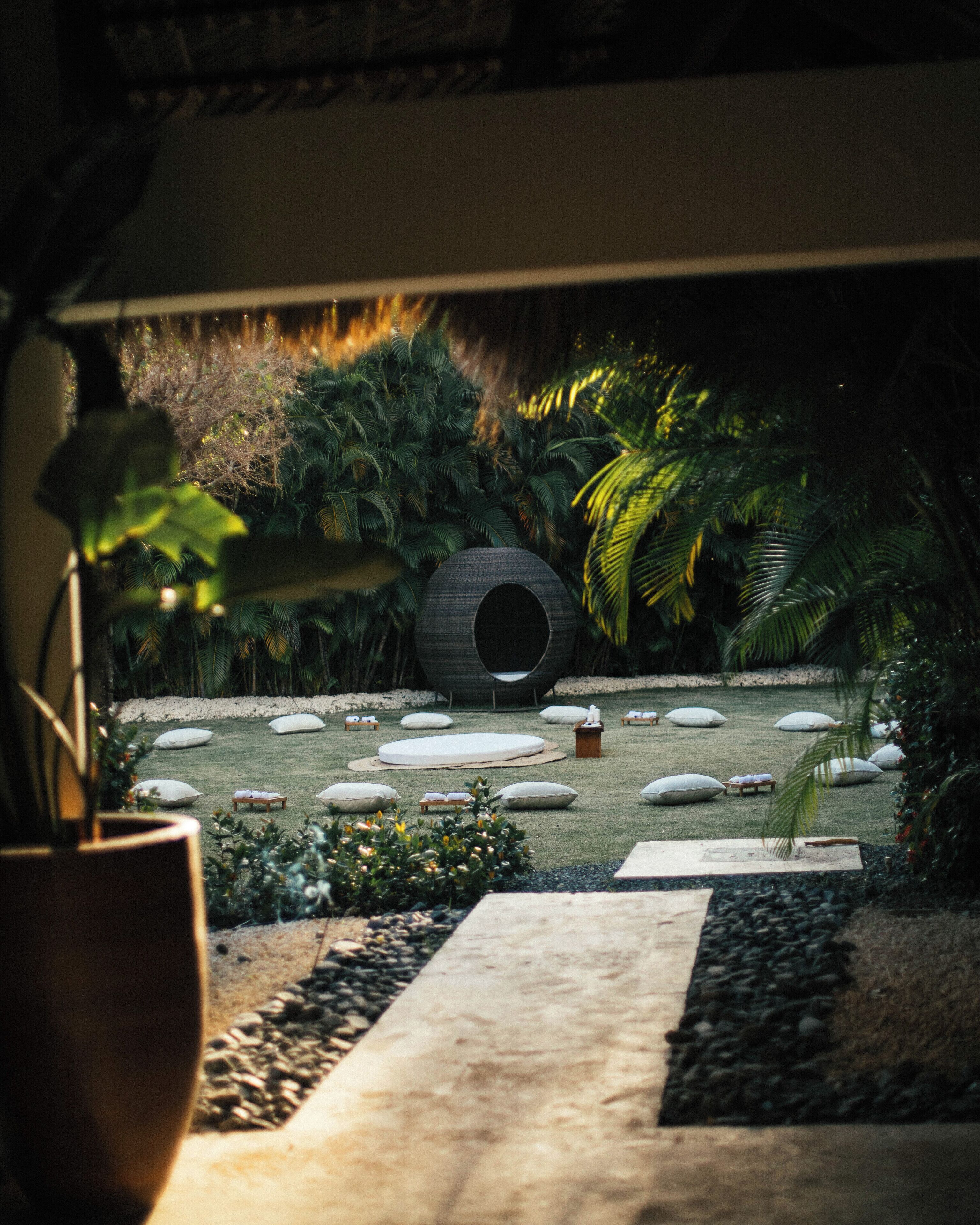 A garden with a circular structure, white cushions, and a pathway.
