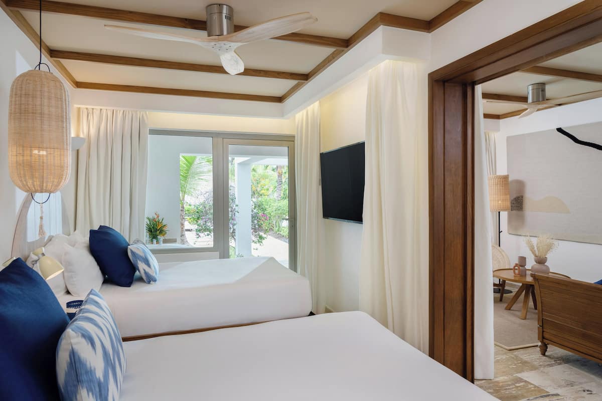 Habitación de hotel con cama, ventilador de techo, televisor y vista al exterior.